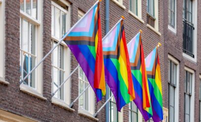 a picture of 4 inclusive pride flags hanging on a red brick building